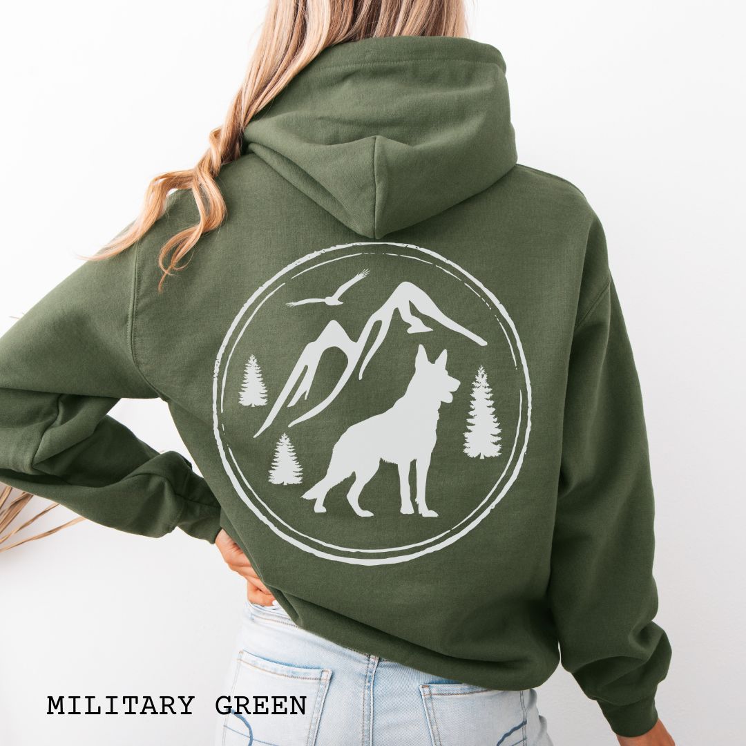 Military Green Gildan 18500 German Shepherd Mountain Adventure hoodie featuring a large vintage-style back print with GSD silhouette, mountains, pine trees, and birds for hiking and outdoor dog lovers.