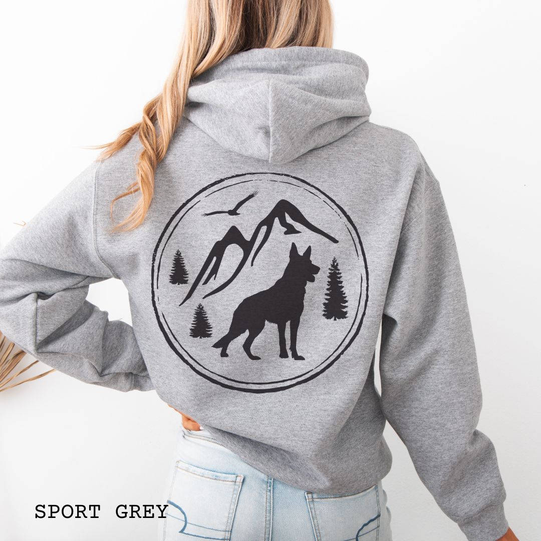 Sport grey Gildan 18500 German Shepherd Mountain Adventure hoodie featuring a large vintage-style back print with GSD silhouette, mountains, pine trees, and birds for hiking and outdoor dog lovers.