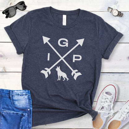 Heather navy IGP dog t-shirt with a graphic of crossed arrows, the letters IGP, and silhouette of a German Shepherd Dog, displayed on a wooden surface with a pair of jeans and white shoes in the background.