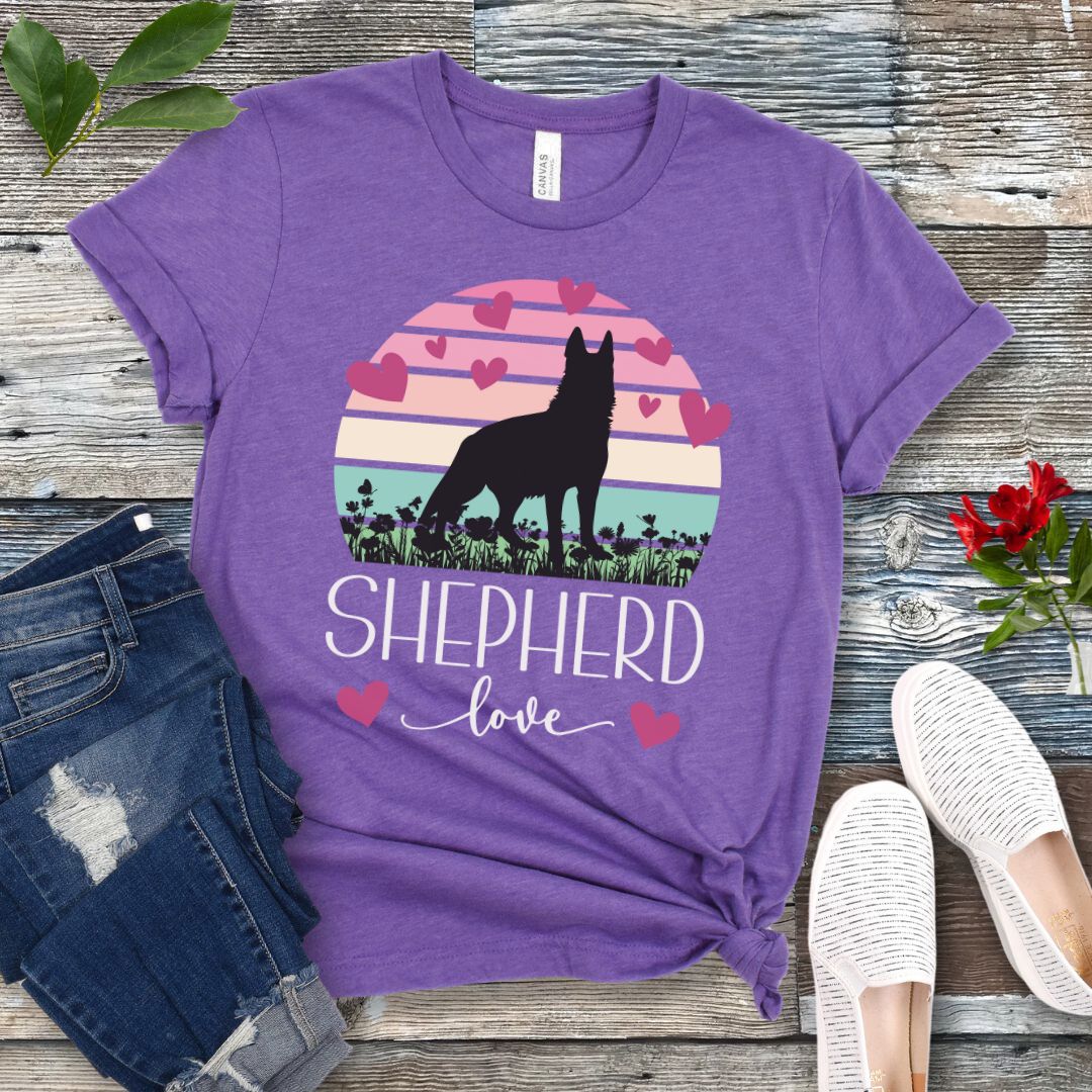 Purple t-shirt with pastel vintage sunset, hearts, German Shepherd dog and the text Shepherd Love' in feminine script, presented on a wooden surface with jeans and shoes.