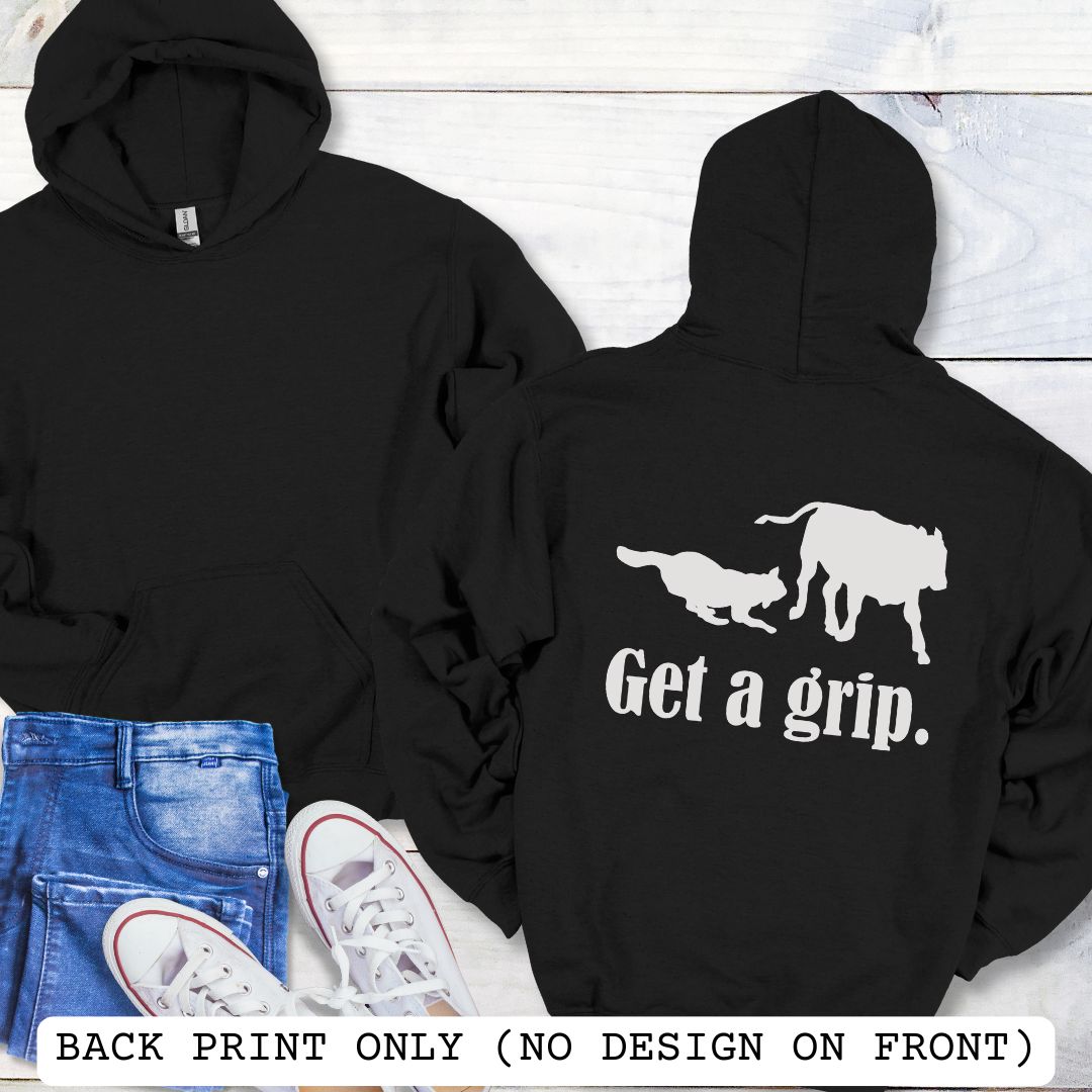 A black back print hoodie with a graphic of a Heeler dog herding a cow and the text 'Get a grip.' Presented on a wood surface with accessories.