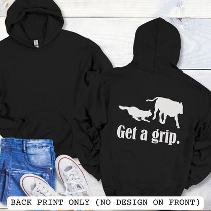 A black back print hoodie with a graphic of a Heeler dog herding a cow and the text 'Get a grip.' Presented on a wood surface with accessories.