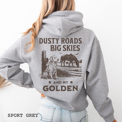 Back view of person wearing gray hoodie featuring a Western-style design with grazing horse, rustic fence, and a Golden Retriever illustration; text reads “Dusty Roads, Big Skies, and My Golden.”