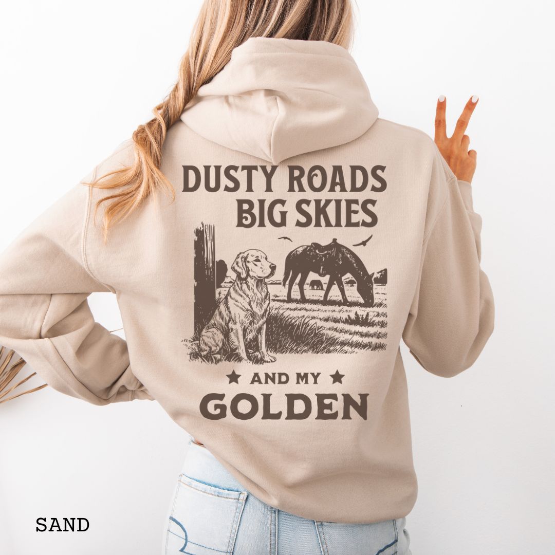Back view of sand-beige hoodie featuring a Western-style design with grazing horse, rustic fence, and a Golden Retriever illustration; text reads “Dusty Roads, Big Skies, and My Golden.”