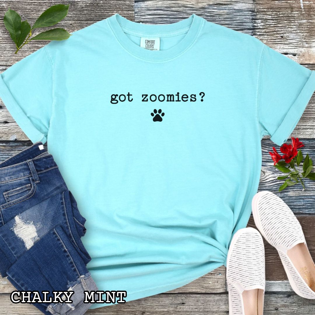 Mint Comfort Colors t-shirt featuring the humorous text 'Got Zoomies?' with paw print graphic, a funny dog lover shirt for dog owners, puppy parents, dog training enthusiasts, dog walkers and fans of dog behavior humor.