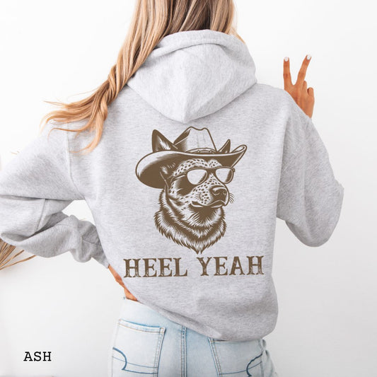 Light grey Australian Cattle Dog hoodie with a graphic of a Heeler dog in cowboy hat and sunglasses,  and 'HEEL YEAH' text on the back, worn by a person.