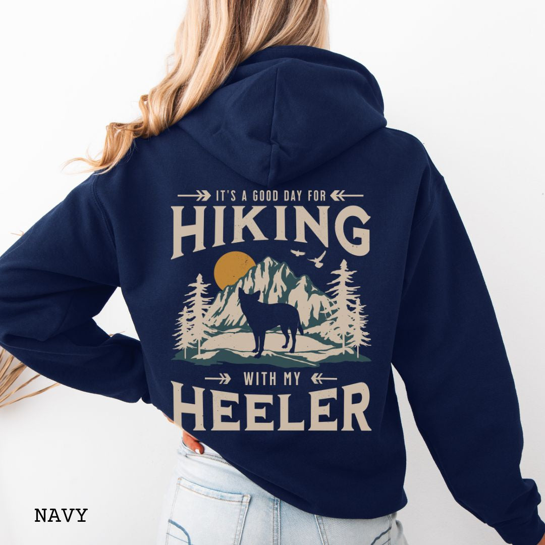 Navy back print dog lover hoodie with vintage mountain graphic, Australian Heeler and 'It's a Good Day for Hiking With My Heeler' text, worn by a person.