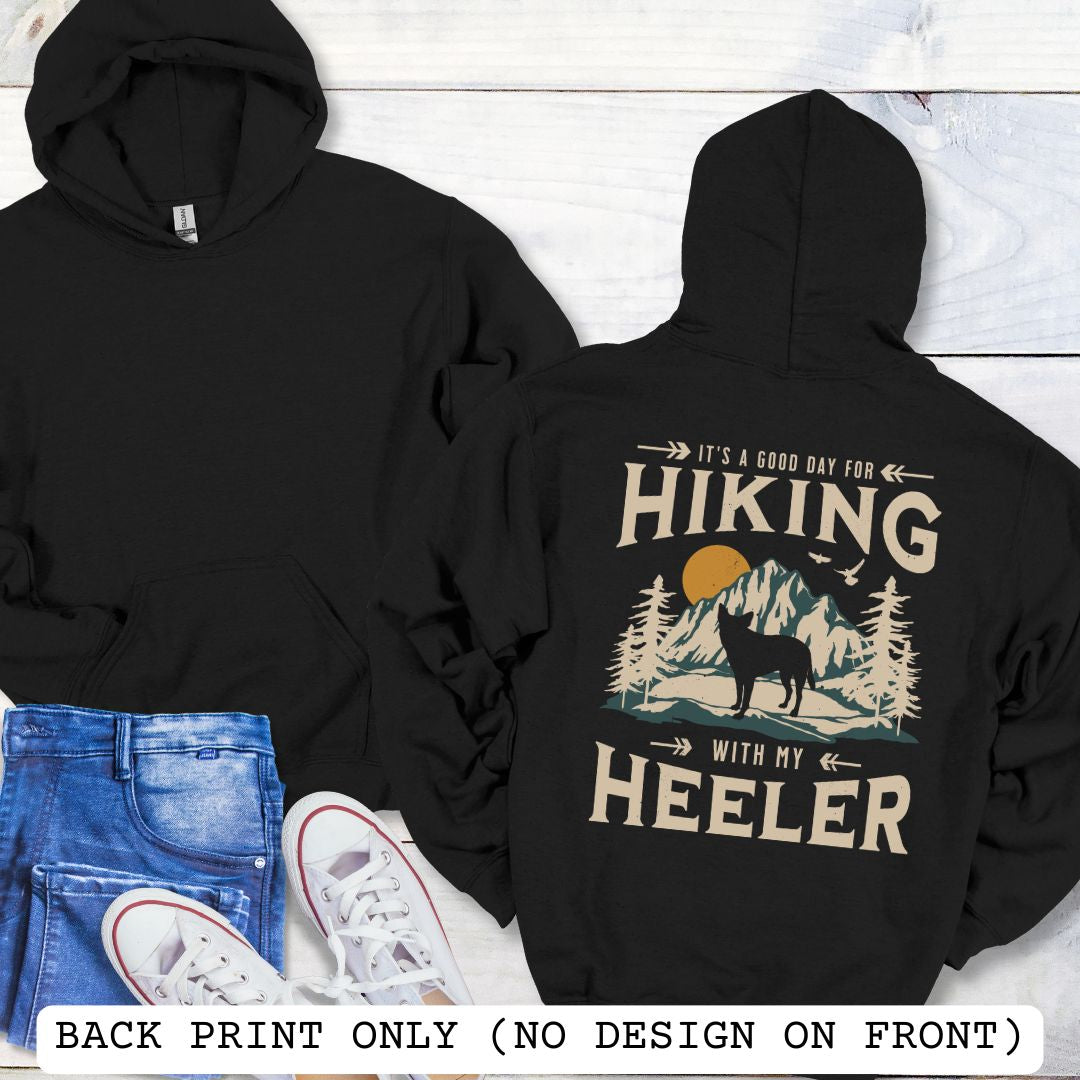 Black back print dog lover hoodie with vintage mountain graphic, Australian Heeler and 'It's a Good Day for Hiking With My Heeler' text, worn by a person.