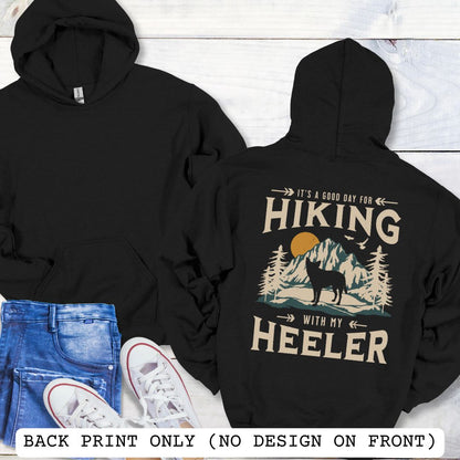 Black back print dog lover hoodie with vintage mountain graphic, Australian Heeler and 'It's a Good Day for Hiking With My Heeler' text, worn by a person.