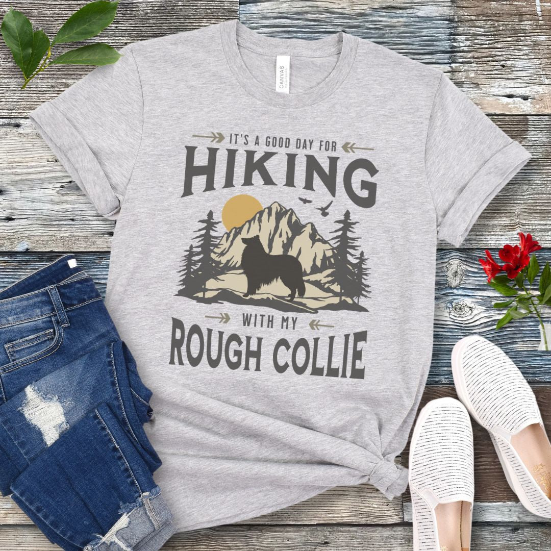 Grey Collie lover t-shirt with vintage mountain scene graphic, a rough collie silhouette and text 'It's a Good Day For Hiking With My Rough Collie', shown on a wooden surface with jeans and shoes.