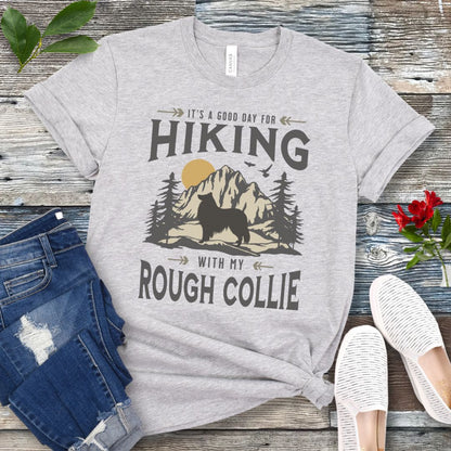Grey Collie lover t-shirt with vintage mountain scene graphic, a rough collie silhouette and text 'It's a Good Day For Hiking With My Rough Collie', shown on a wooden surface with jeans and shoes.