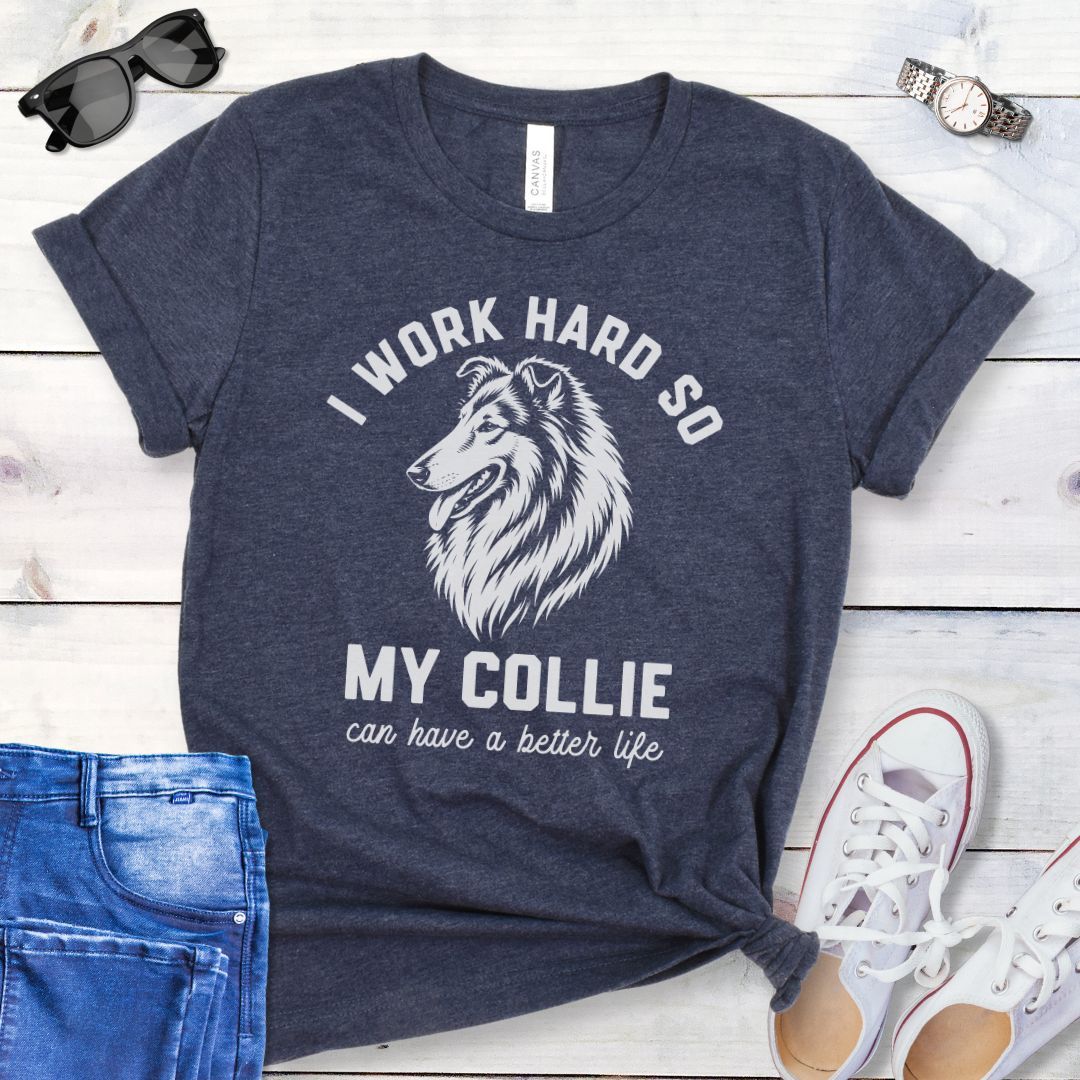 Heather navy blue unisex t-shirt for Rough Collie lovers with linocut-style breed head study graphic and humorous text 'I work hard so my Collie can have a better life', shown on a wooden surface with jeans and shoes. 