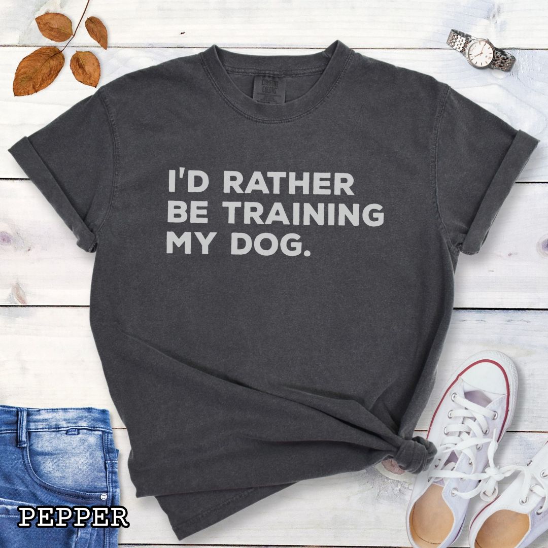 Dark gray (Pepper) Comfort Colors t-shirt with 'I'd rather be training my dog' text on a light wooden surface with shoes and jeans.