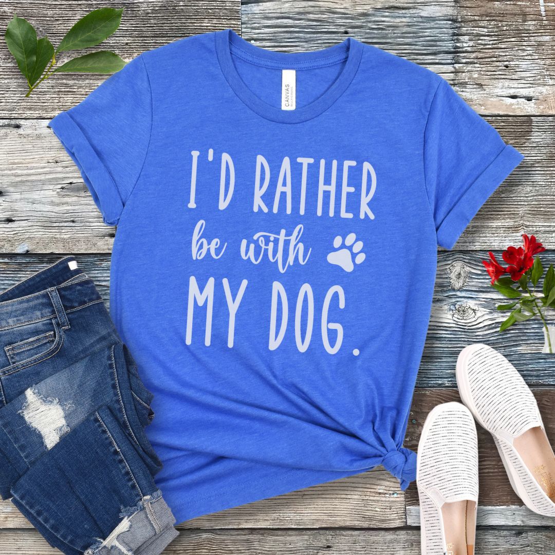 Blue t-shirt with 'I'd rather be with my dog' text on a wooden surface with jeans and shoes.