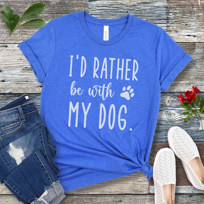 Blue t-shirt with 'I'd rather be with my dog' text on a wooden surface with jeans and shoes.