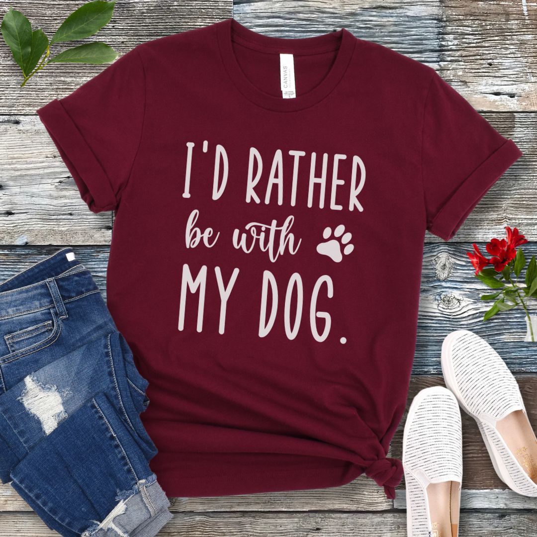 Maroon t-shirt with 'I'd Rather be with my dog' text on a wooden surface with jeans and shoes.