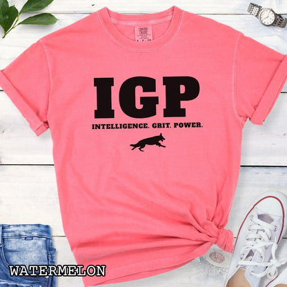 Pink Comfort Colors t-shirt featuring the IGP Intelligence. Grit. Power. design with working dog silhouette, Schutzhund shirt for IGP competitors, IPO handlers, protection sports enthusiasts, and working dog trainers.