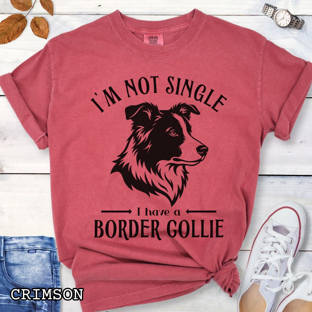 Red Comfort Colors t-shirt with a Border Collie graphic and humorous text 'I'm Not Single, I Have A Border Collie', shown on a wooden surface with jeans and shoes.
