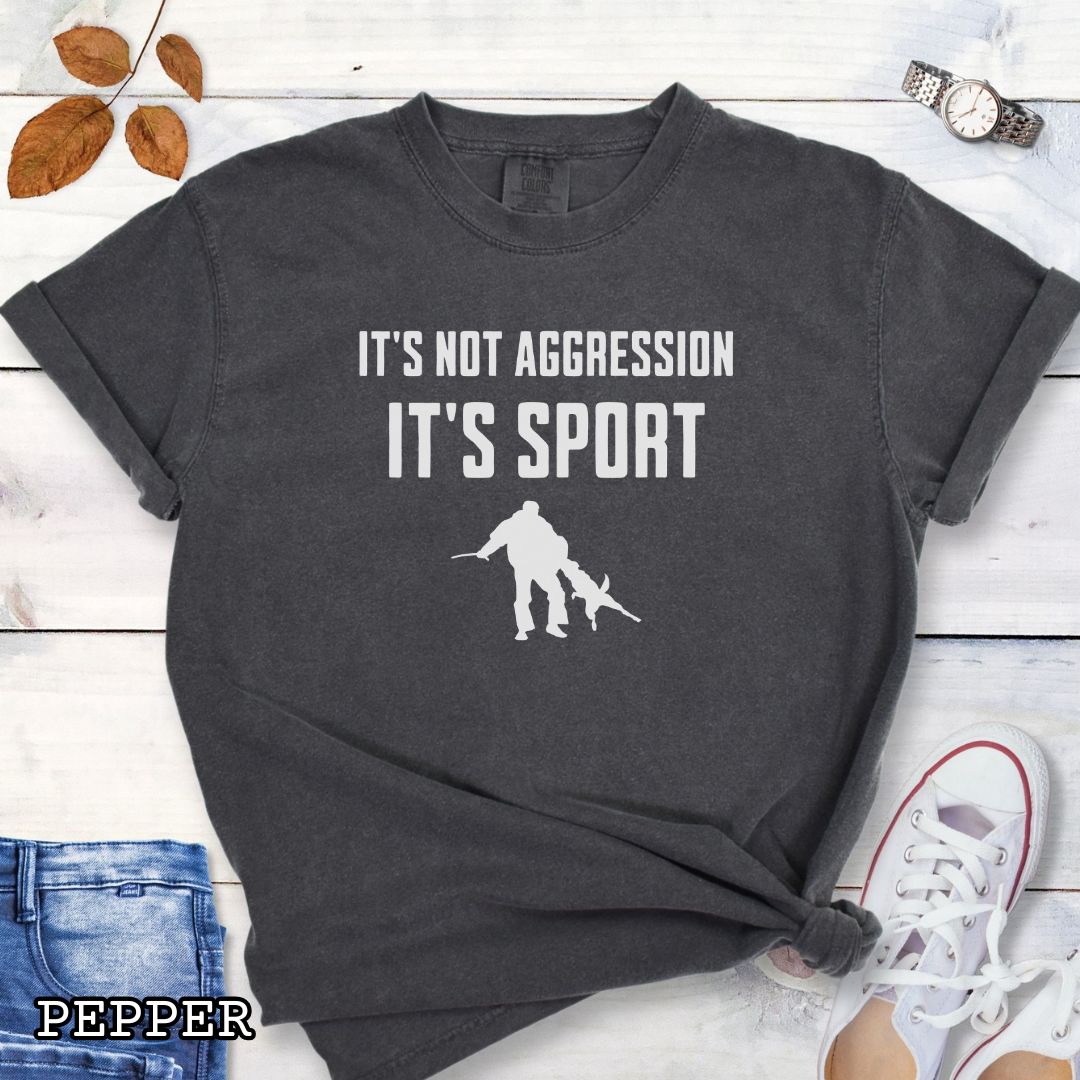 Dark grey Comfort Colors t-shirt for Schutzhund/IGP bitework dog trainers with 'It's not aggression, it's sport' text and a bite work graphic, shown on a wooden surface.