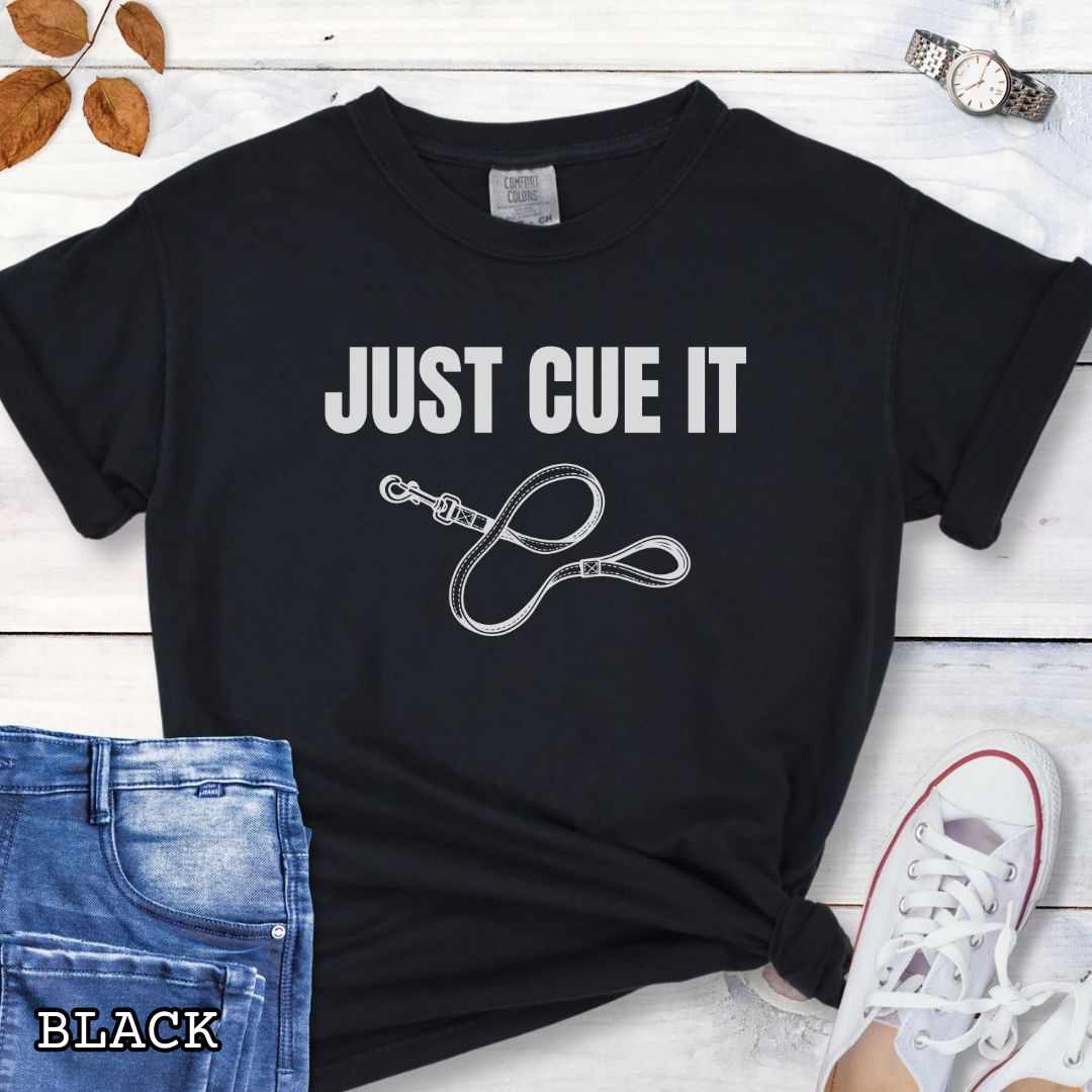 Black Comfort Colors t-shirt featuring a Just Cue It text with leash graphic, a positive reinforcement dog training shirt for dog trainers and reward-based training enthusiasts.