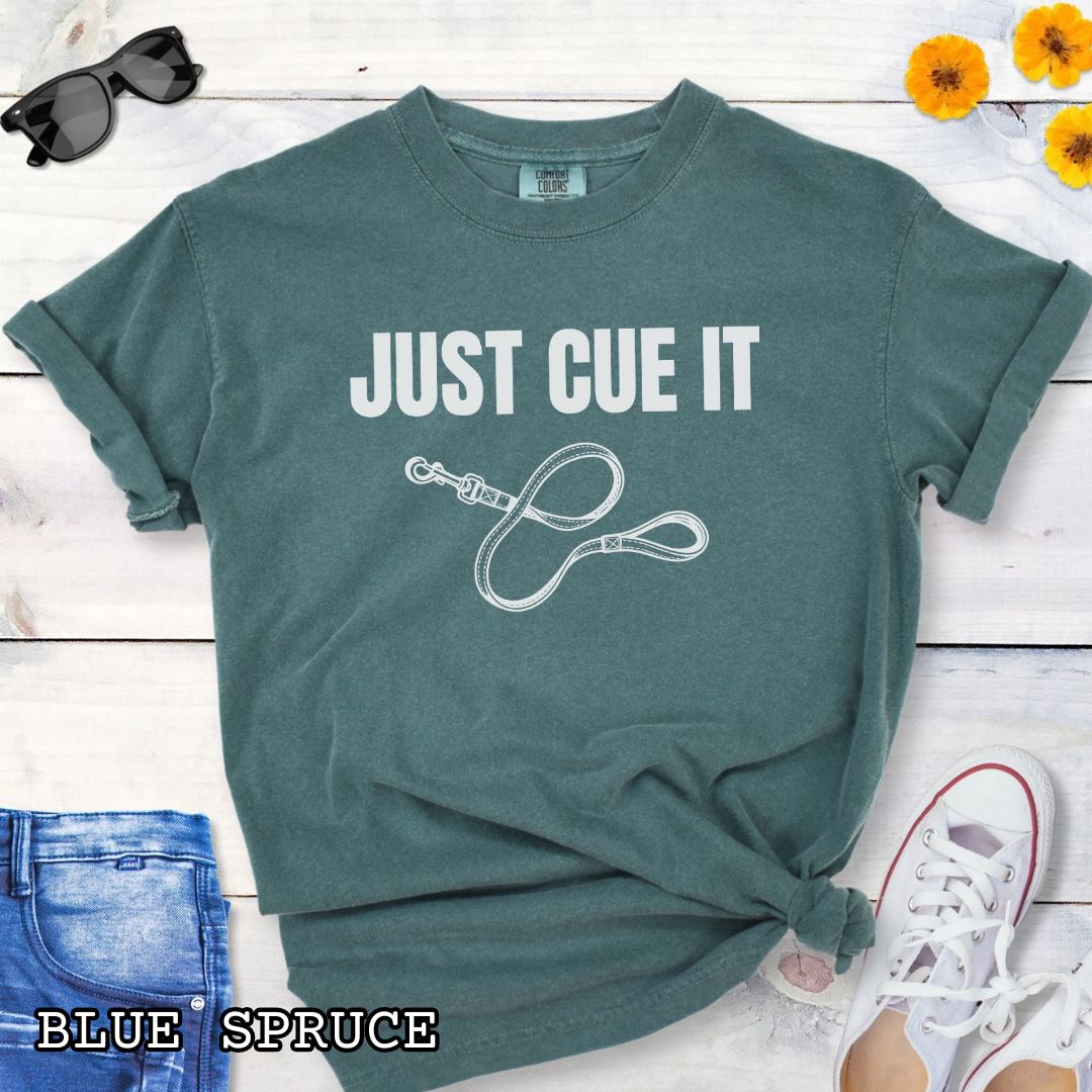 Green Comfort Colors t-shirt featuring a Just Cue It text with leash graphic, a positive reinforcement dog training shirt for dog trainers and reward-based training enthusiasts.