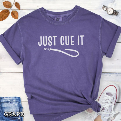 Purple Comfort Colors t-shirt featuring a Just Cue It text with leash graphic, a positive reinforcement dog training shirt for dog trainers and reward-based training enthusiasts.
