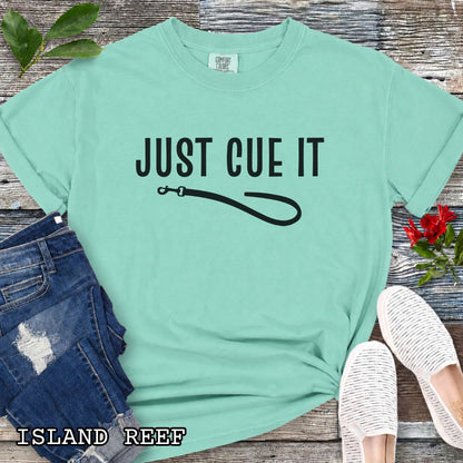 Green-teal Comfort Colors t-shirt featuring a Just Cue It text with leash graphic, a positive reinforcement dog training shirt for dog trainers and reward-based training enthusiasts.