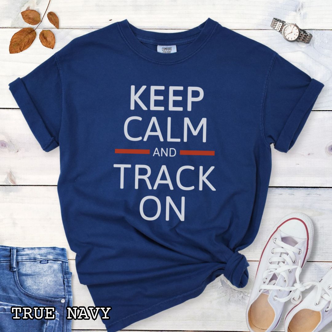 Navy blue dog tracking training t-shirt with 'Keep Calm and Track On' in bold text on a wooden surface with jeans and sneakers.
