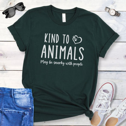 Green unisex t-shirt for pet and animal lovers with humorous text 'Kind to Animals May be snarky with people' in playful lettering, shown on a wooden surface with accessories.