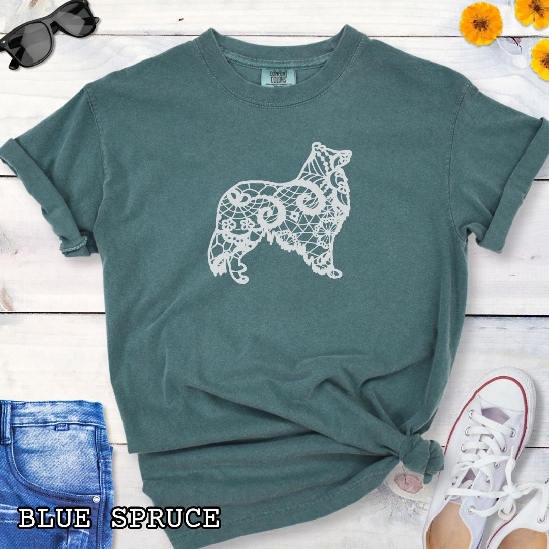 Green Comfort Colors t-shirt with a white  Rough Collie silhouette filled with faux-lace pattern, shown on a wooden surface with shoes and jeans.