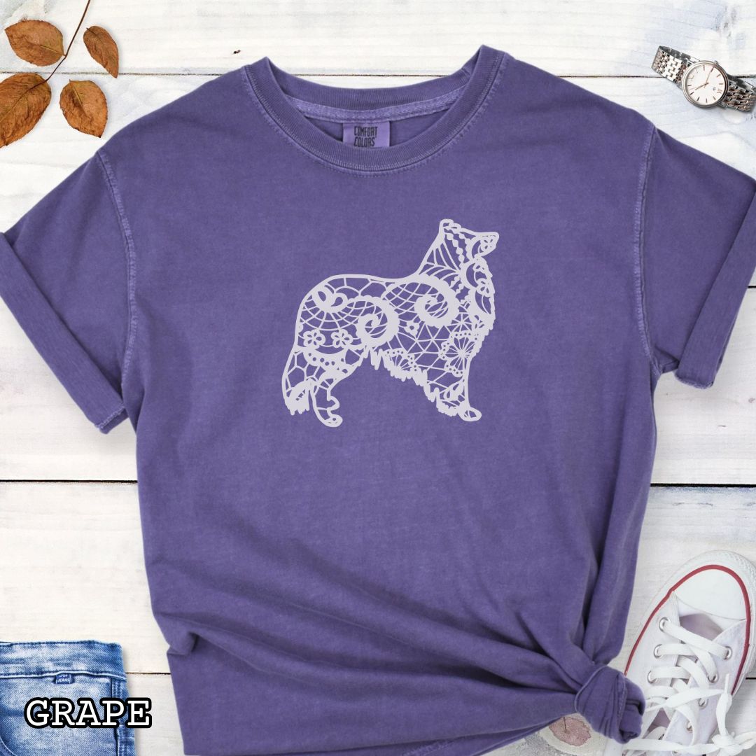 Purple Comfort Colors t-shirt with a white  Rough Collie silhouette filled with faux-lace pattern, shown on a wooden surface with shoes and jeans.