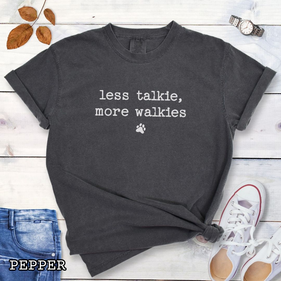 Grey (pepper) Comfort Colors dog lover t-shirt with 'less talkie, more walkies' text on a wooden surface with jeans and sneakers.