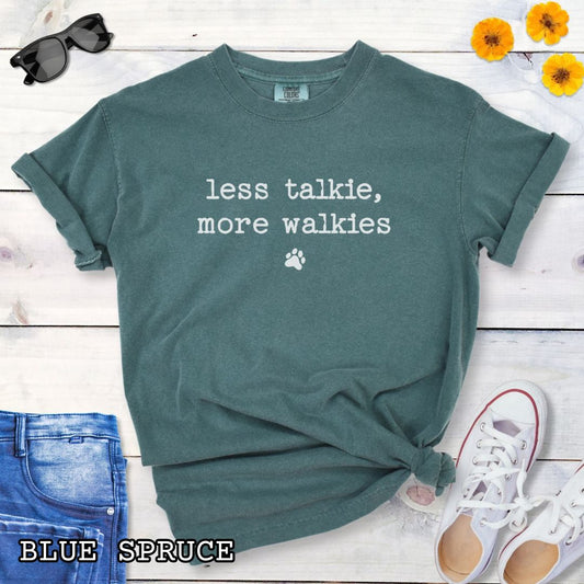 Green (Blue Spruce) Comfort Colors dog lover t-shirt with 'less talkie, more walkies' text on a wooden surface with jeans and sneakers.
