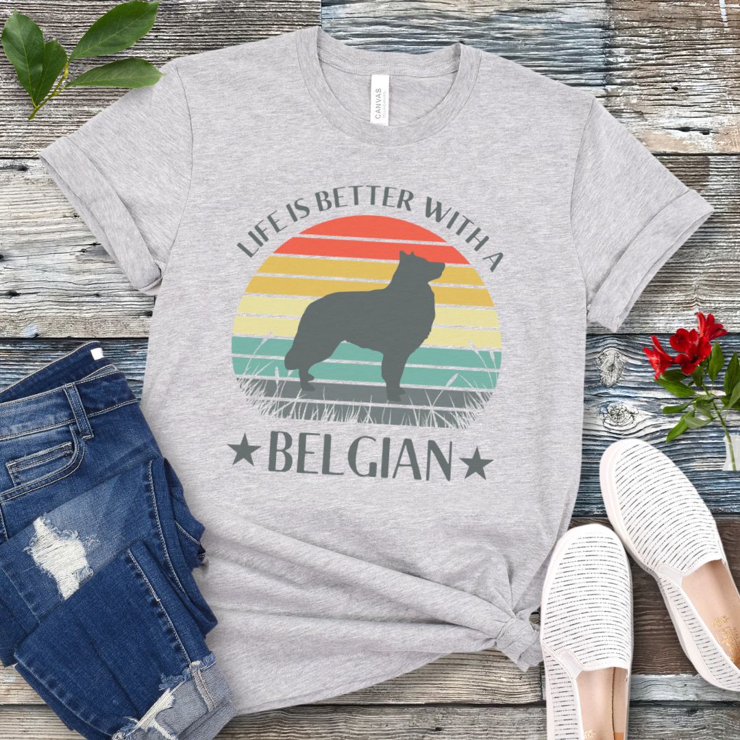 Grey t-shirt for Belgian Sheepdog lovers with a retro sunset graphic design featuring a Belgian Sheepdog silhouette and text 'Life is better with a Belgian', shown on a wooden surface.