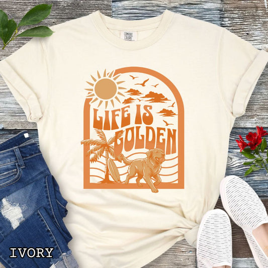 Comfort Colors ivory Golden Retriever beach t-shirt featuring retro tropical sunset design with palm trees, surfboard, and Life Is Golden slogan, perfect for Golden Retriever lovers, beach dog moms, and summer dog lover gifts.