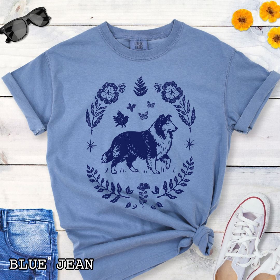 Blue Comfort Colors t-shirt with folk art style Rough Collie t-shirt featuring a linocut-inspired collie surrounded by floral and botanical elements in a boho cottagecore design. Perfect dog lover gift for Collie owners.