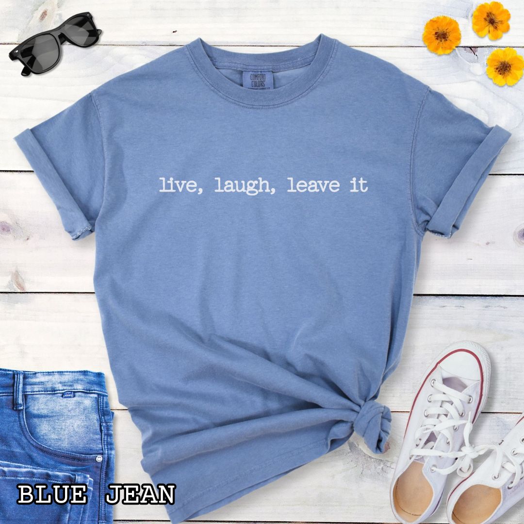 Blue (Blue Jean) Comfort Colors dog training t-shirt with 'live, laugh, leave it' text on a wooden surface with jeans and shoes.