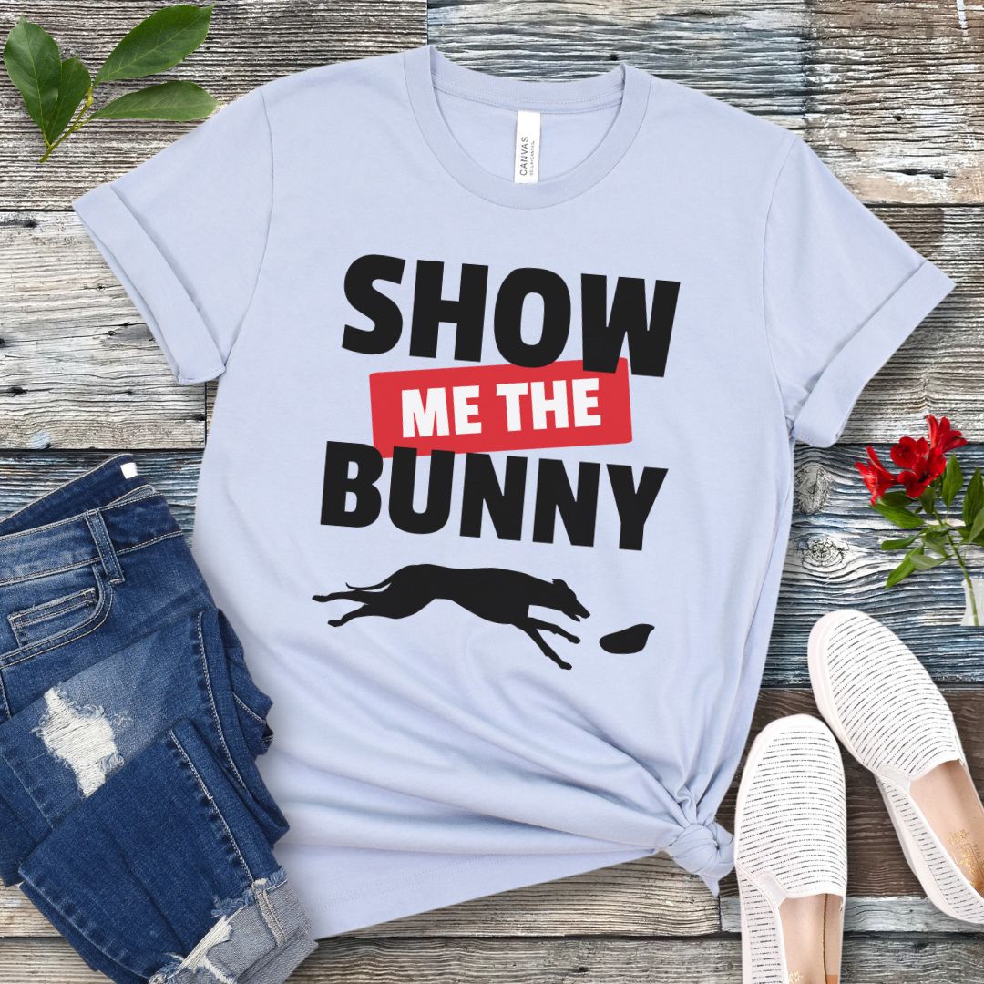 Light blue lure coursing t-shirt with bold 'Show Me The Bunny' text and sighthound graphic on a wooden surface with jeans and shoes.