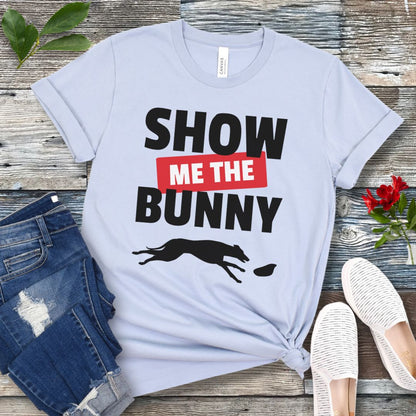 Light blue lure coursing t-shirt with bold 'Show Me The Bunny' text and sighthound graphic on a wooden surface with jeans and shoes.