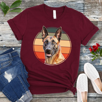 Maroon t-shirt for Belgian Malinois lovers with a vintage sunset graphic and Malinois face, shown on a wooden surface with jeans and shoes.