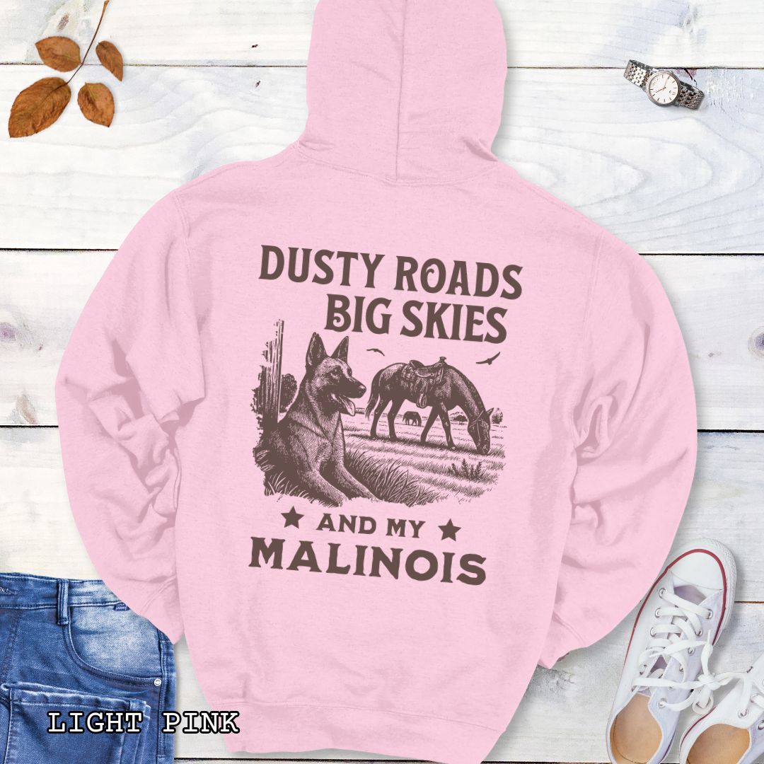 Back view of a light pink Belgian Malinois hoodie featuring a Western-style design with grazing horse, rustic fence, and a Malinois illustration; text reads “Dusty Roads, Big Skies, and My Malinois.”