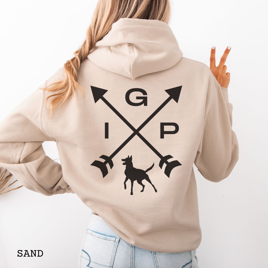 Beige Schutzhund/IGP hoodie with crossed arrows design with 'IGP' text and Belgian Malinois on the back, presented on a wooden surface with accessories.