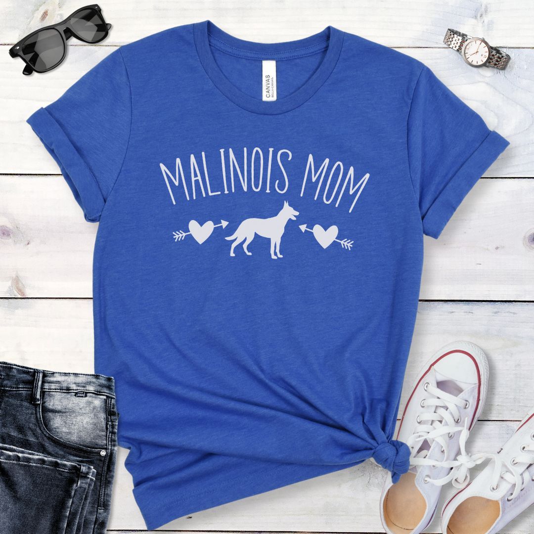Royal blue t-shirt for Belgian Malinois lovers with 'Malinois Mom' text in feminine lettering, and a Belgian Malinois silhouette accompanied by arrow-pierced heart graphics. Shown  on a wooden surface with jeans and shoes.