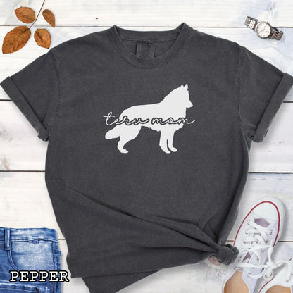 Dark grey Comfort Colors t-shirt with Belgian Tervuren silhouette and 'Terv Mom' text in handwritten script lettering, shown on a wooden surface with denim jeans and a flower.