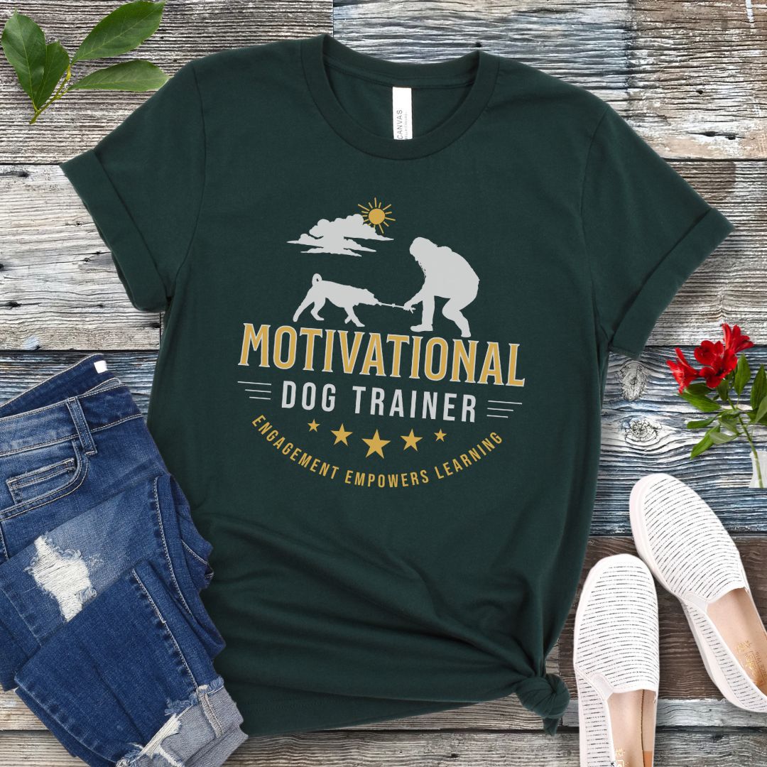 Green t-shirt with 'Motivational Dog Trainer' design on a wooden surface with jeans and shoes.