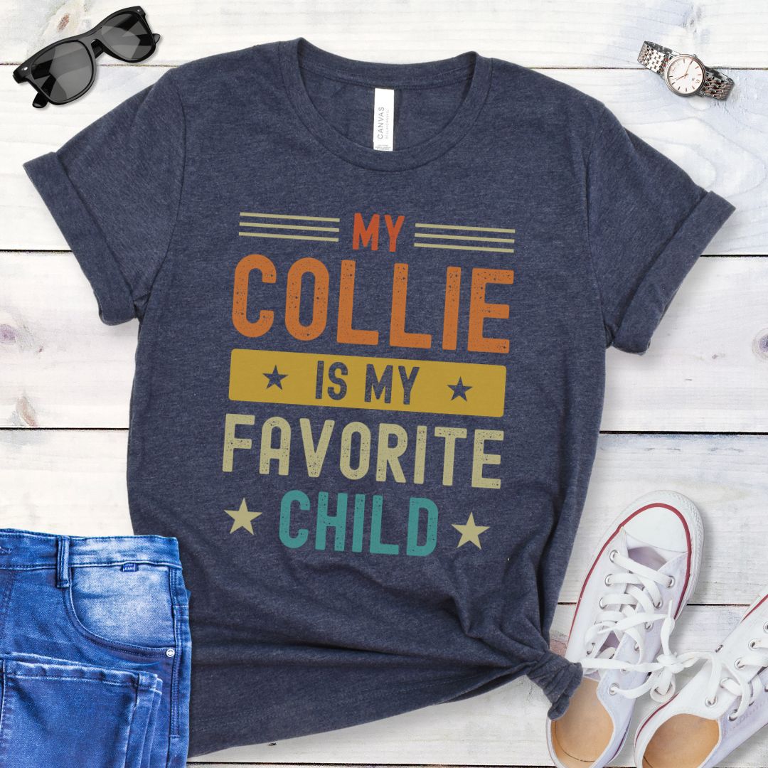 Heather navy t-shirt for Rough Collie lovers with humorous text 'My Collie is my Favorite Child' in bold colorful retro lettering, shown on a wooden surface with jeans and shoes.