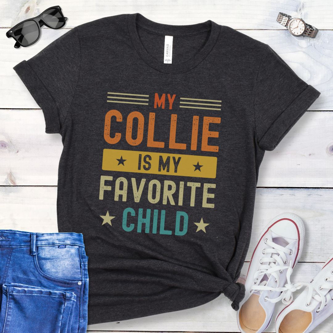 Dark grey t-shirt for Rough Collie lovers with humorous text 'My Collie is my Favorite Child' in bold colorful retro lettering, shown on a wooden surface with jeans and shoes.