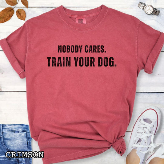Red Comfort Colors t-shirt featuring the phrase Nobody Cares. Train Your Dog., funny dog training shirt for dog trainers, obedience handlers, dog sports competitors, responsible dog owners, and canine training enthusiasts.