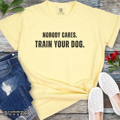 Yellow Comfort Colors t-shirt featuring the phrase Nobody Cares. Train Your Dog., funny dog training shirt for dog trainers, obedience handlers, dog sports competitors, responsible dog owners, and canine training enthusiasts.