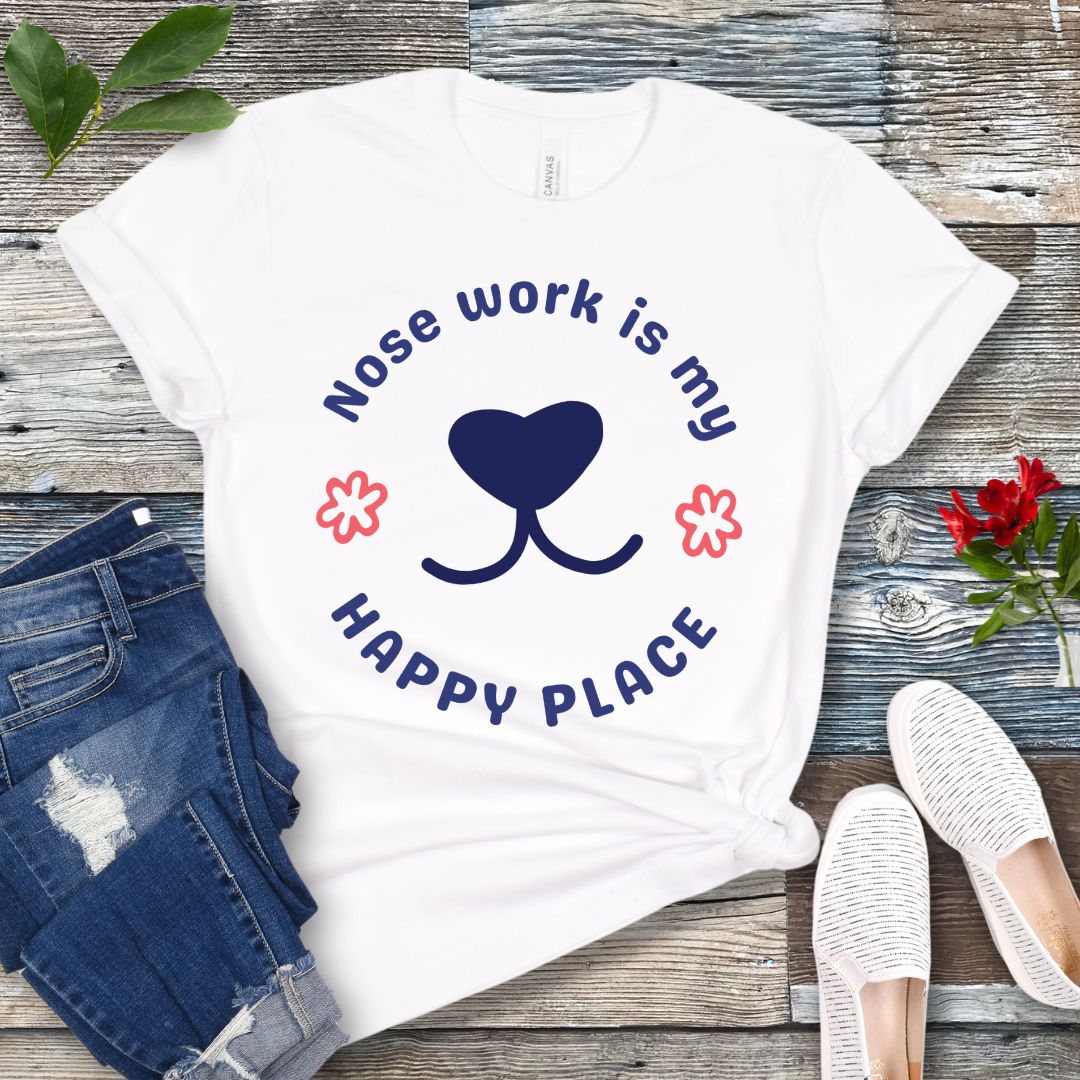 White nosework for dogs t-shirt with 'Nose work is my happy place' text with dog nose design, shown on a wooden surface with jeans and shoes.